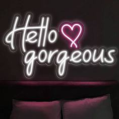 a neon sign that says hello gorgeous with a heart in the middle on a bed