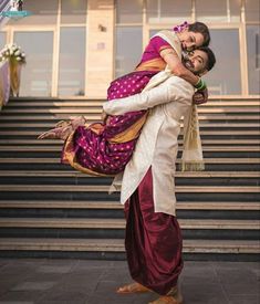 a man carrying a woman on his back while standing in front of stairs with an umbrella