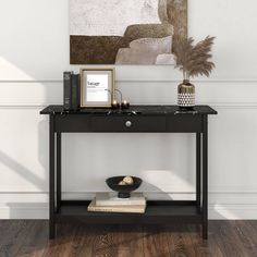 a black console table with two books and a vase on the shelf next to it