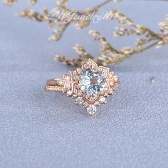 an engagement ring with a blue topazte surrounded by white and pink flowers on a light blue background