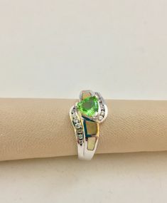 Tsavorite Garnet, Trillion, 6 x 6mm,  .60ct min. Cream color Mother of Pearl shoulders  Diamond simulate CZ accents,  Criss Cross design  925 Sterling Silver. US SIZE 7 Would make a beautiful engagement ring or a gift for that special someones January Birthday as Garnet is that months birthstone. Go the extra mile and get a garnet tha isn't the same ole red garnet everyone seems to have to mark their birth month. Classic Green Heart Cut Rings, Formal Green Heart Cut Rings, Green Diamond Accented Promise Ring Jewelry, Green Gemstone Rings With Heart Cut, Green Gemstone Heart Cut Rings, Green Heart Cut Jewelry With Center Stone, Green Heart Cut Center Stone Jewelry, Green Emerald Ring With Diamond Accents In Sterling Silver, Sterling Silver Jewelry With Lime Green Accent Stones