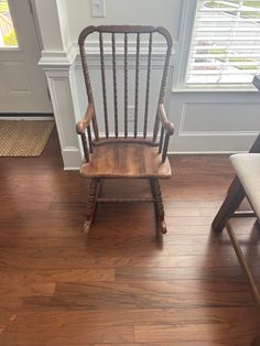 a wooden rocking chair sitting on top of a hard wood floor next to a window