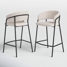 two stools with arms and legs, one in white upholstered fabric the other in black metal