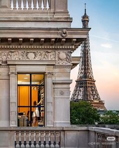 the eiffel tower is in the background as people look out from an open window