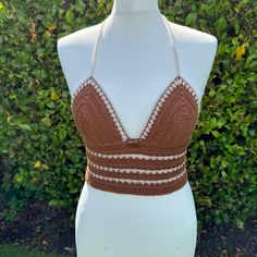 Handmade brown and beige Crochet Bralette Crop Top with adjustable tie back and glass bead embellishment. This top is made in a high quality beautiful brown yarn with beige details and features a fully adjustable halterneck tie, and a fully adjustable tie up back. It also features a bronze glass bead in the front center.  Due to its customisable nature, this top would fit someone between the sizes of UK 6/8 to UK14. Approximate cup size A - C. Displayed on a UK size 8/10 mannequin.  PLEASE NOTE - since this is a handmade item, its rather delicate so we recommend hand washing it only! Fitted Brown Halter Neck Crop Top, Fitted Brown Halter Top For Festivals, Fitted Brown Halter Top For Beach, Festival Brown Crochet Lace Top, Fitted Bohemian Brown Crop Top, Brown Fitted Triangle Halter Top, Fitted Brown Triangle Halter Top, Bohemian Brown Crochet Top For Festival, Brown Fitted Crop Top For Vacation