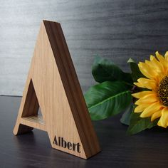 a wooden triangle with the word albert on it next to a sunflower