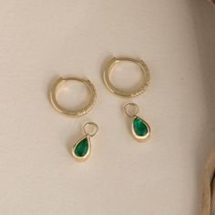 Malia These huggie hoops aren't your average. Crafted in gleaming 14k solid gold (available in yellow, rose, or white), they hug your earlobes in a chic, close-fitting style. But the real magic unfolds with the detachable charm. Each charm features a captivating pear-cut emerald, a gemstone known for its mesmerizing depth of color. Buy them separately to add a touch of emerald elegance to your existing huggies or upgrade with our diamond lined huggie hoops – the perfect pairing for instant glam. Real Magic, Rose Gold Charms, Jewellery Wedding, Necklace Design, Natural Emerald, Gold Charm, Gold Hoop, Pear Cut, Huggies Earrings