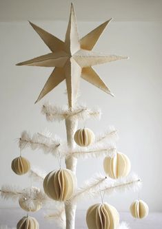 a white christmas tree with ornaments hanging from it's sides and a star on top