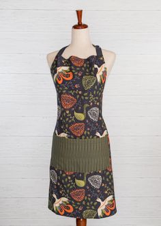 an apron on a mannequin wearing a dress with fruit and vegetables printed on it