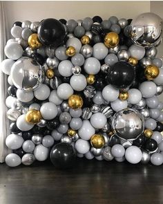 a bunch of balloons that are on the floor in front of a wall with gold and silver balls