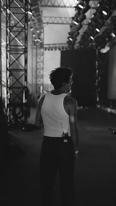 black and white photograph of a man with tattoos on his arm standing in front of a stage