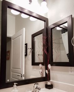 a bathroom sink with two mirrors above it