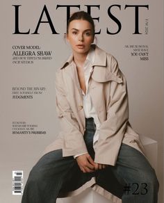 a woman sitting on top of a white box wearing a trench coat and jeans, posing for the cover of latest magazine