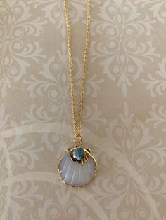 "Gold tone and white scalloped shell necklace with blue stone accent, shell necklace, scallop shell pendant, blue stone necklace, shell bead necklace, shell pendant, shell jewelry Coloring of blue stone may vary some from picture.   Pendant measures 7/8\" l X 7/8\" W and is on an 18\" chain.   ★ Want to see more?  Please visit my shop at: https://www.etsy.com/shop/DesignsByPeg" Sea Inspired Necklace, Clam Shell Necklace, Scallop Shell Necklace, Blue Shell-shaped Necklaces, Blue Shell-shaped Ocean-inspired Necklace, Ocean-inspired Blue Shell-shaped Necklace, Blue Ocean-inspired Shell-shaped Necklace, Shell Pendant Necklace, Blue Shell-shaped Jewelry For Gift