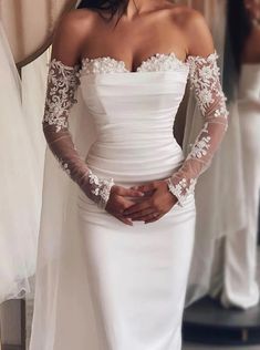 a woman wearing a white wedding dress with sheer sleeves and an off the shoulder lace top