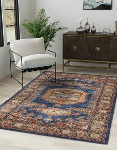 a living room area with a rug, chair and sideboard