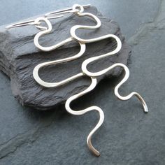 These large sterling silver wave earrings are a real statement piece! They are made from thick silver wire, which I've formed into undulating curves and waves for a bohemian look. I've beaten the tips of the curves to add detail and strength. The earwires are also sterling and are hand forged. Despite their size these earrings are relatively lightweight and have a lovely movement when worn. They'd make a great gift for any fan of contemporary silver jewellery and are sure to get you noticed! Measurements Total length from top of ear wires: 8cm (3 1/8") Wave section length: 6.5cm (2 1/2") Width at widest point: 3cm (1 1/8") Sent nicely gift wrapped in turquoise tissue and an organza pouch, if you prefer a gift box these can be found separately in my shop. Please note this item does not arri Handmade Silver Wavy Jewelry, Handmade Sterling Silver Earrings With A Modern Twist, Contemporary Silver Jewelry, Wave Earrings, Wave Necklace, Bohemian Look, Unusual Design, Lovely Earrings, Earrings Statement