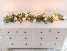 flowers and candles are placed on top of a dresser