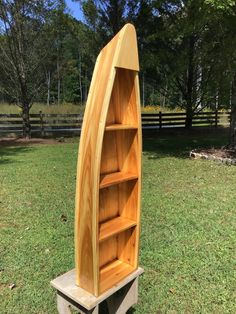 a wooden boat shaped book shelf sitting in the grass