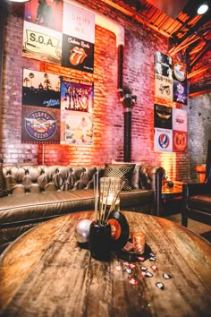 a living room with couches, tables and posters on the brick wall behind it