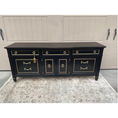 a black and gold dresser with four drawers on the front, two doors open to reveal a door