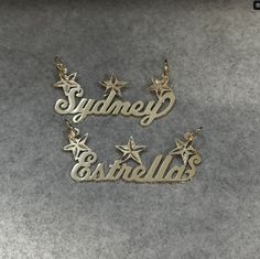 two name necklaces with star charms in gold and silver, sitting on a gray surface