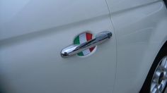 a white car with the italian flag painted on it's door handle and emblem