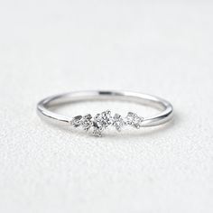 a three stone diamond ring sitting on top of a white surface