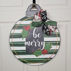 a christmas door hanger with the words be merry on it and holly wreaths