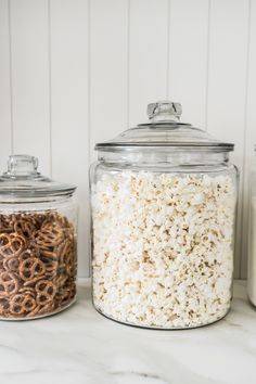 three glass jars filled with different types of cereal and pretzels next to each other