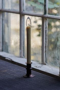 a lit candle sitting on top of a window sill in front of a window