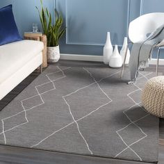 a modern living room with blue walls and white furniture, including a gray area rug