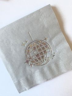 a white napkin with an embroidered globe on it and stars around the edges is sitting on a table