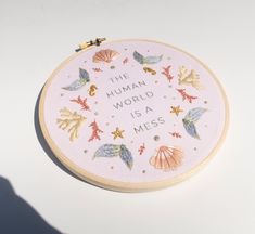 there is a cross stitch pattern on the hoop with words and seashells in it