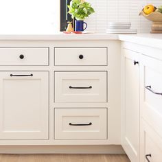 a kitchen with white cabinetry and wood flooring on the counter top, along with a potted plant