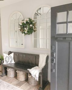 a wooden bench sitting next to two mirrors and baskets on top of a hard wood floor