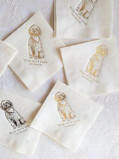 four white napkins with gold foil dogs on them, sitting next to each other