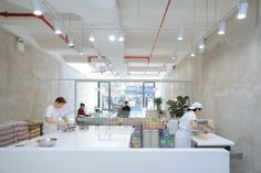 two people are preparing food in a large white room with exposed ceilings and lights on the ceiling