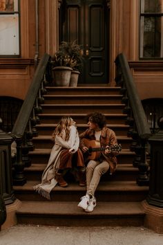 two people sitting on the steps talking and playing guitar