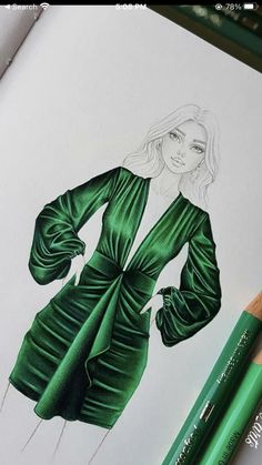 a drawing of a woman's green dress on paper with colored pencils next to it