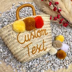 a straw bag with pom - poms on it sitting next to other items