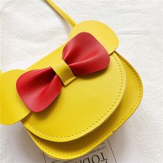 a yellow purse with a red bow on it