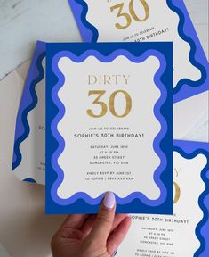 a hand holding up a blue and white birthday card with the number thirty on it