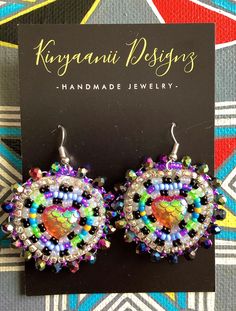 a pair of colorful beaded earrings sitting on top of a black and white card