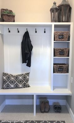 a white bench with some baskets and shoes on top of it in a room that has gray tile flooring