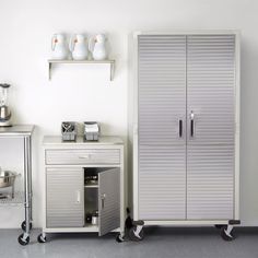 a white cabinet sitting next to a silver cupboard on casteors in front of a wall