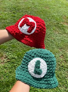 two crocheted hats with the letter q on them are held by someone's hand