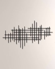 a black metal wall sculpture on the side of a white wall with lines drawn across it