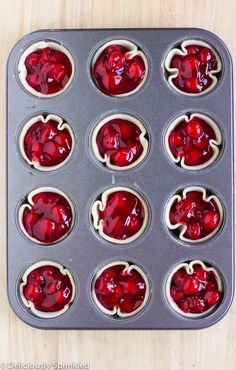 muffin tins filled with cupcake batter and covered in red jello - like toppings