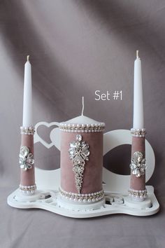 two candles are sitting on a stand with pearls and crystal beads around them, set 1